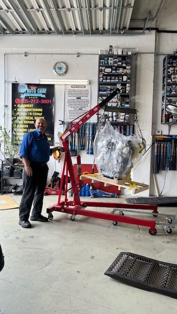 Mecánico profesional reemplazando un motor dañado por uno nuevo en taller automotriz de Miami